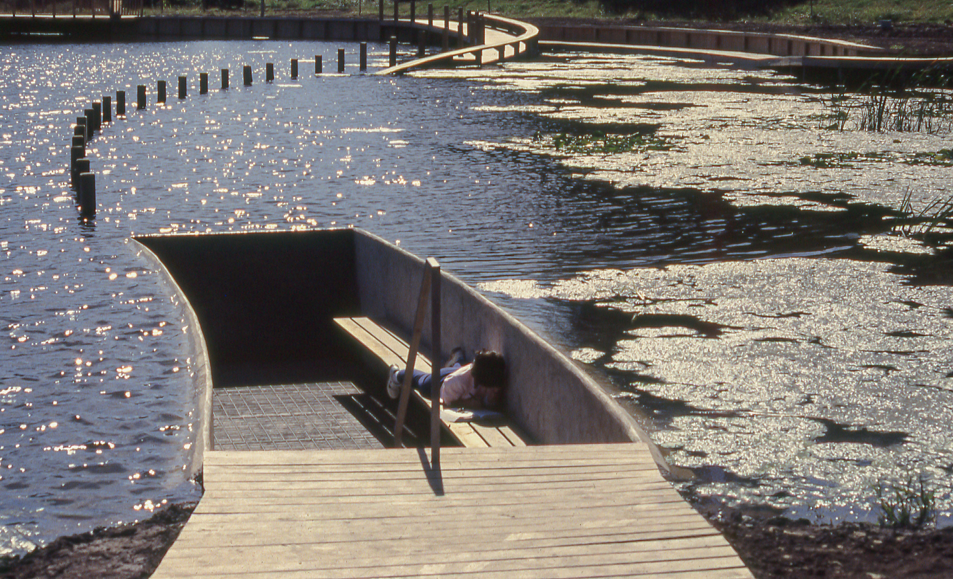 Carved out seat in pond that wooden walkway leads up to at Mary Miss’s “Greenwood Pond: Double Site”