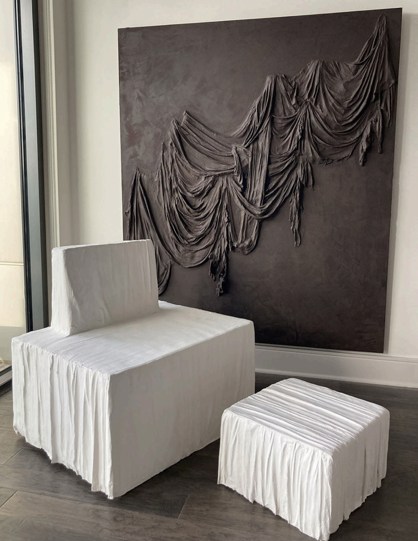 A plaster chair and ottoman in front of the 2022 painting “Draped in Clay Marrón,” all by Curiel