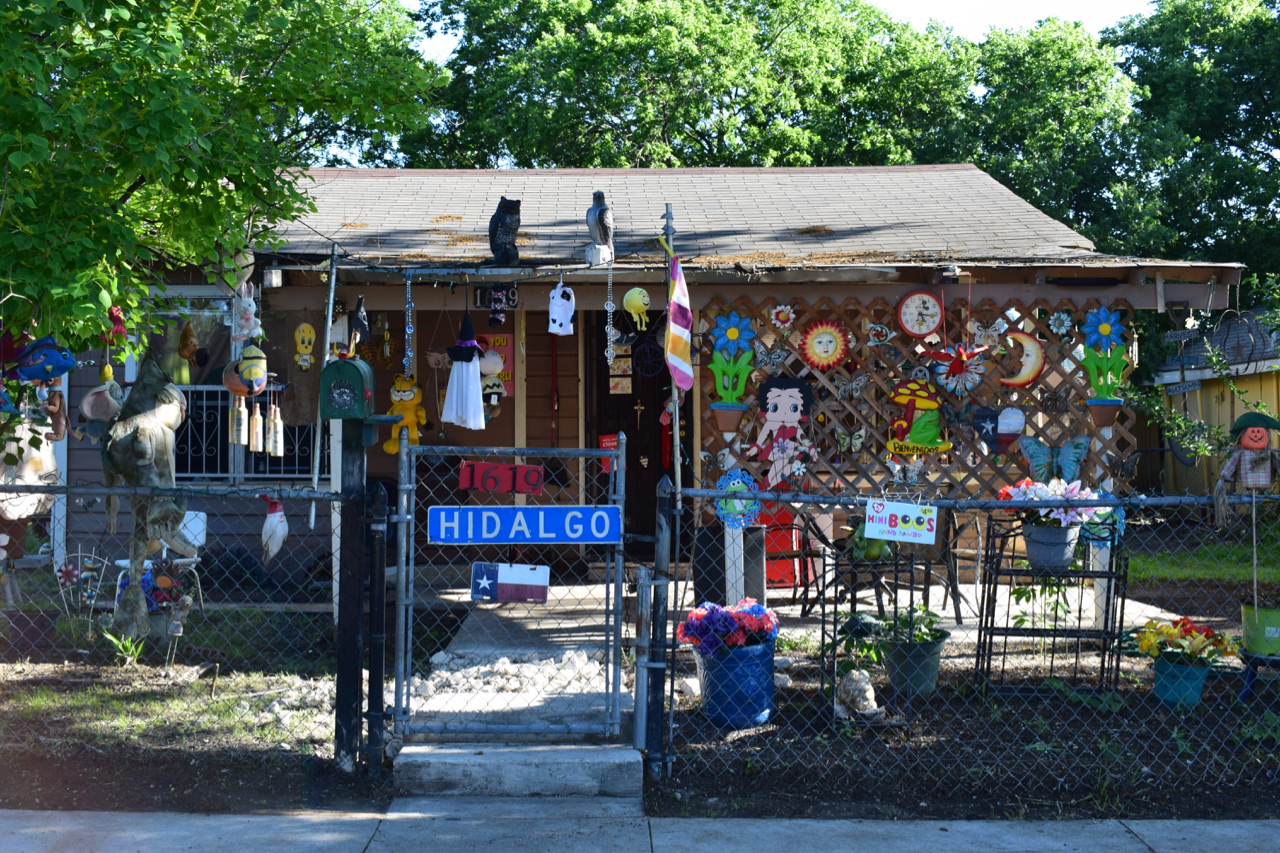 A house with objects and toys dangling off of it behind a fence