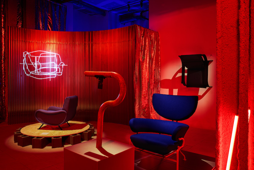 Furniture and lighting in an exhibition against a red background
