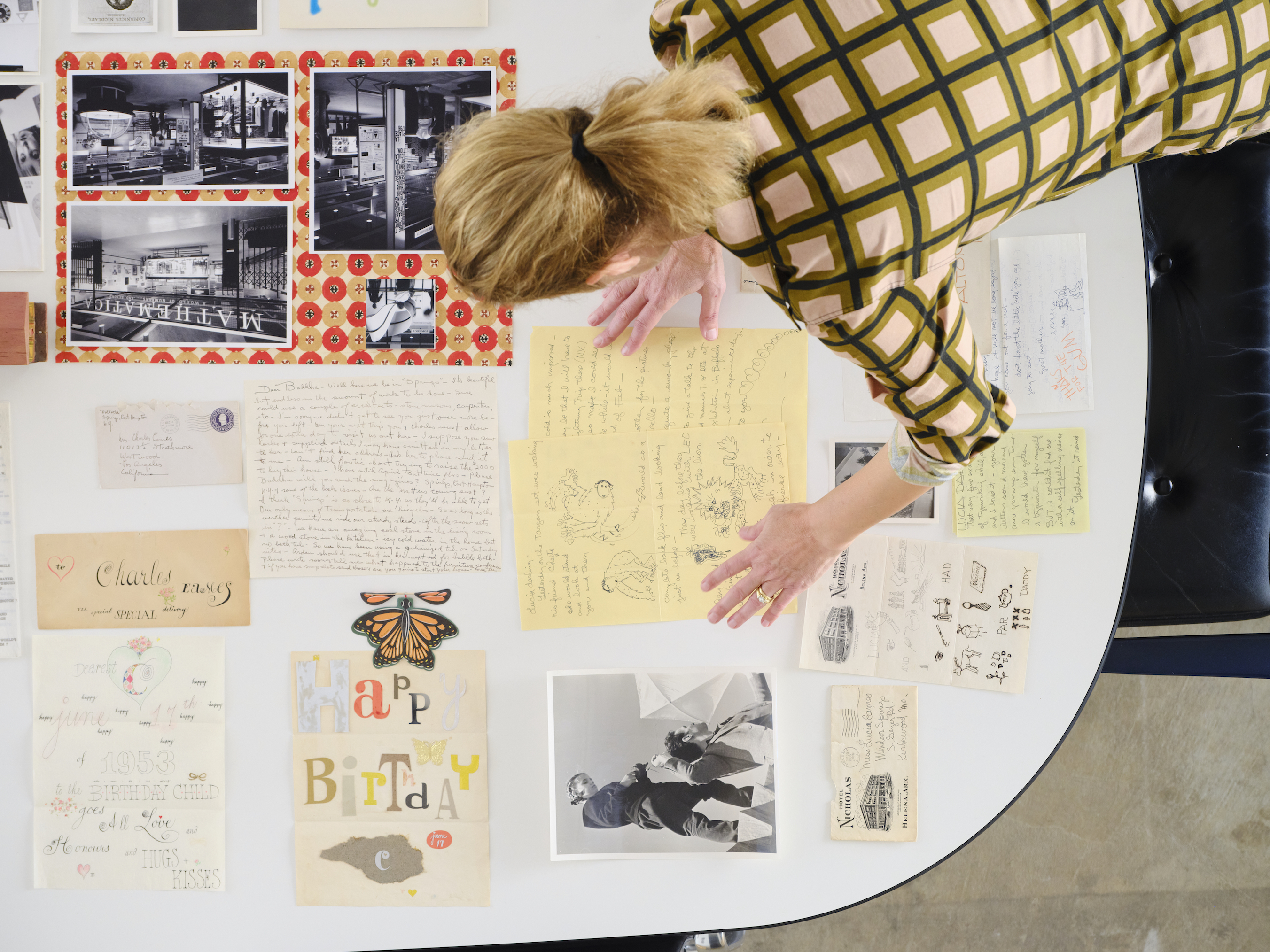 A woman hunched over a series of letters and photographs.