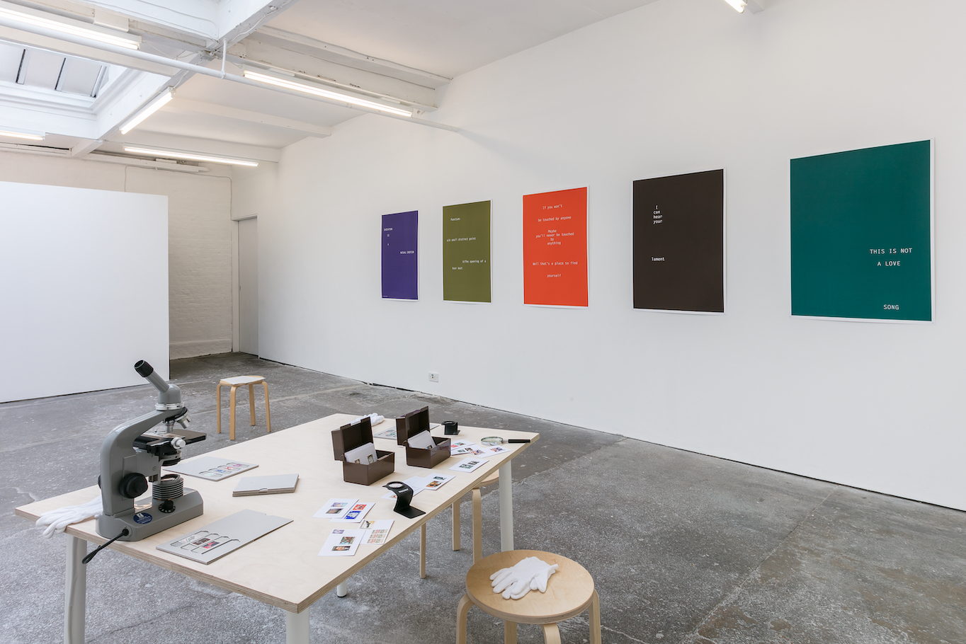 Installation view of an exhibition showing posters and a microscope.