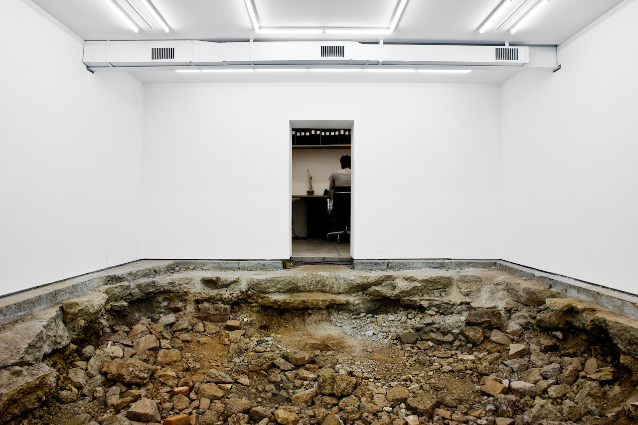 A gallery with the floor dug out to reveal mud and rocks below