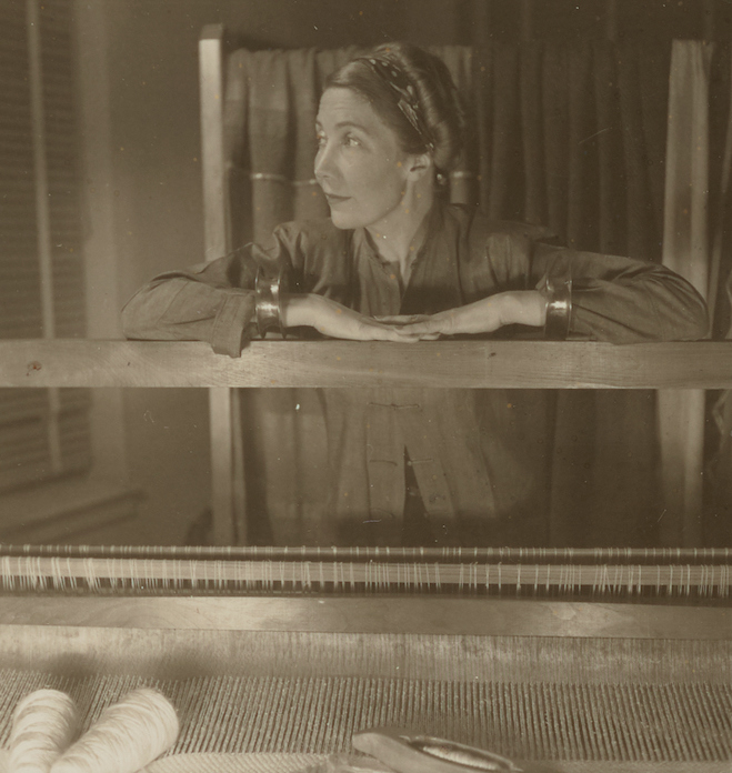 sepia-tone image of young liebes standing and leaning on a loom in her studio