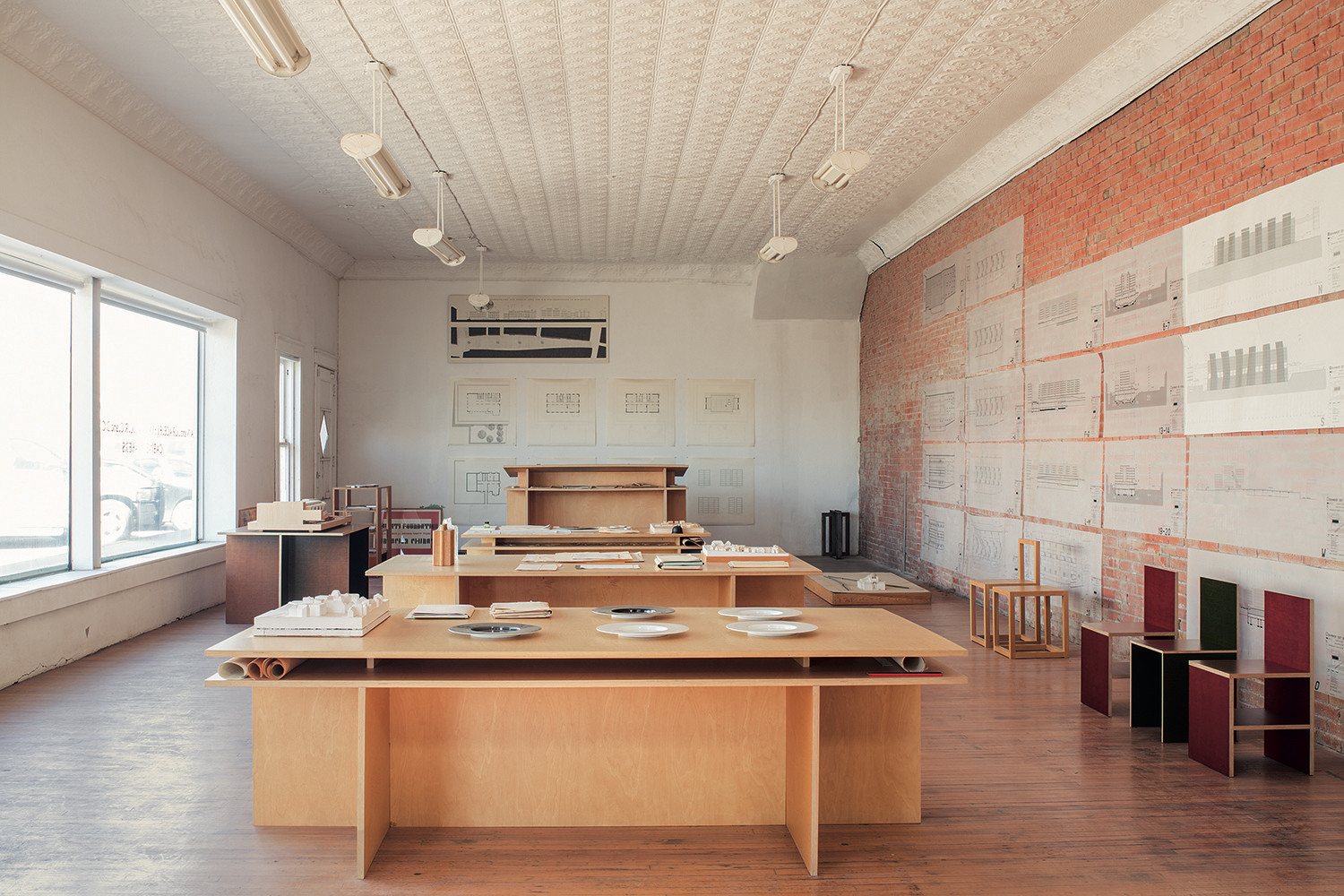 Minimalist white architecture office with exposed brick wall and wooden tables