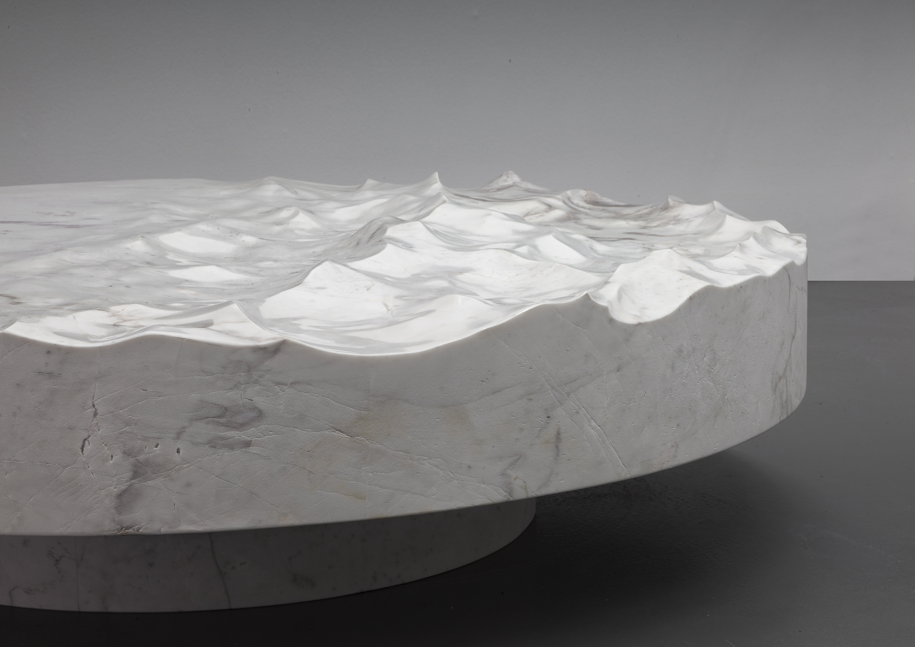 Low circular marble table with wave-textured surface