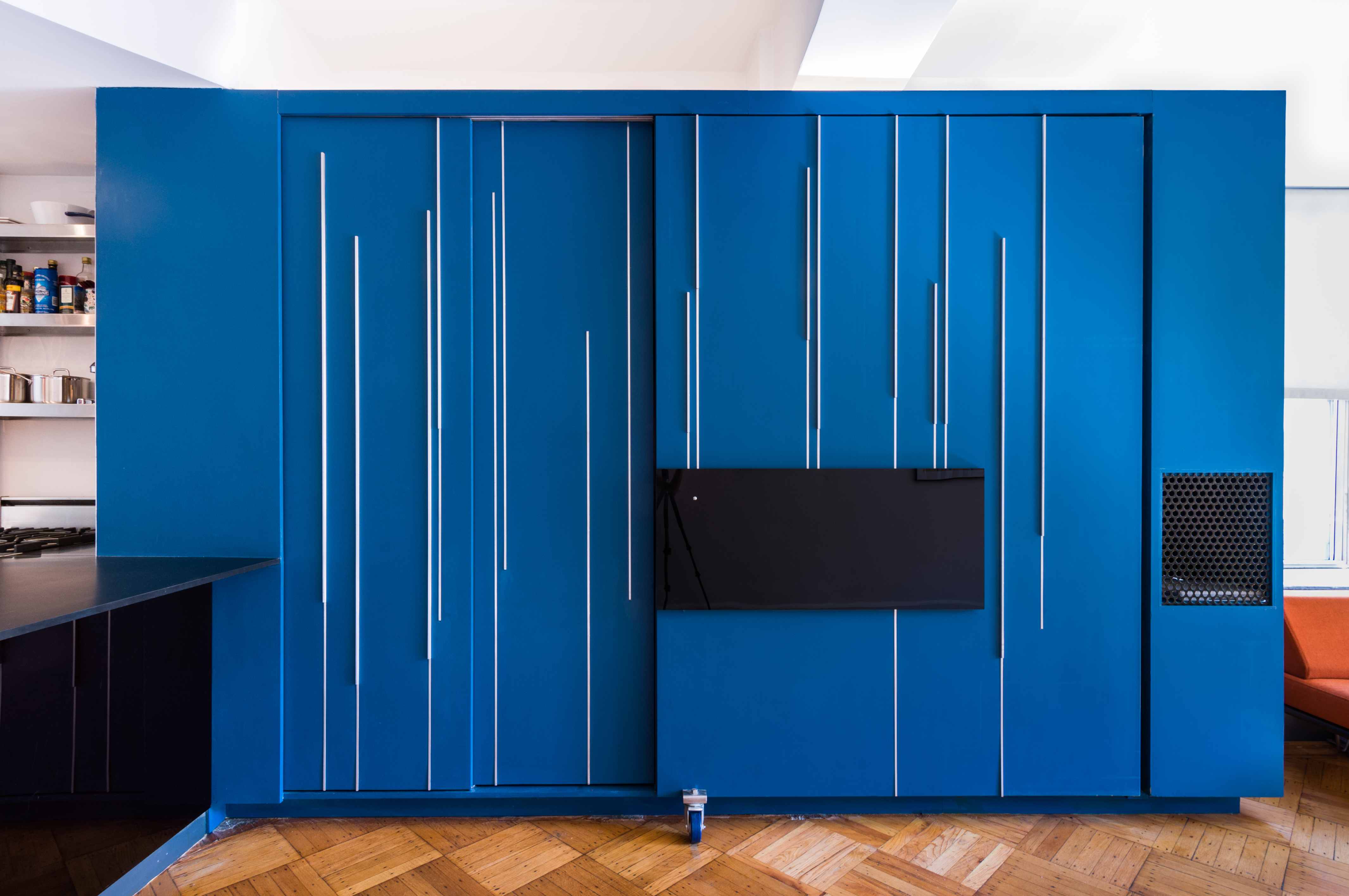 modern cobalt blue unfolding wall that turns into bed and other living spaces inside small apartment