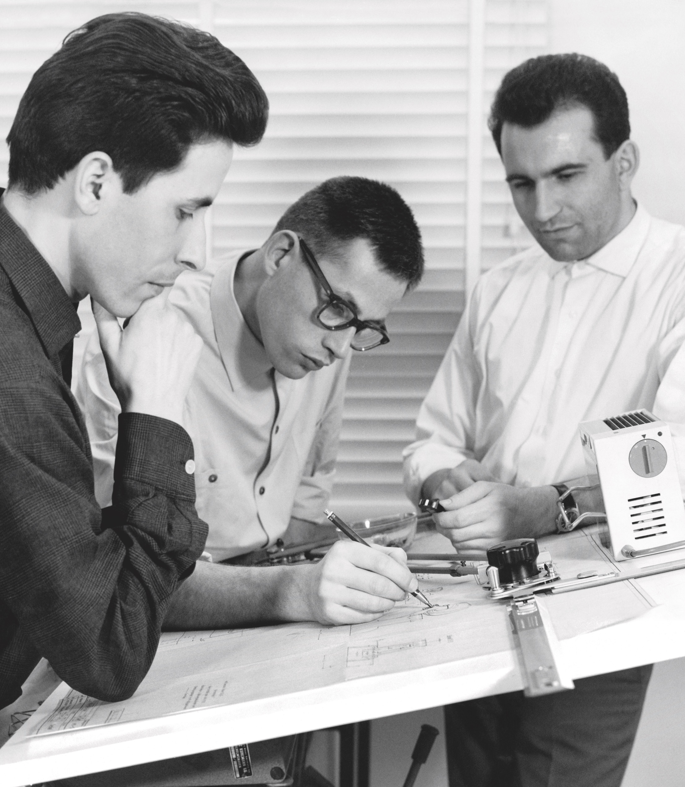 Black and white photo of Reinhold Weiss, Dieter Rams, and Roland Weigend in the Braun design department, around 1961.