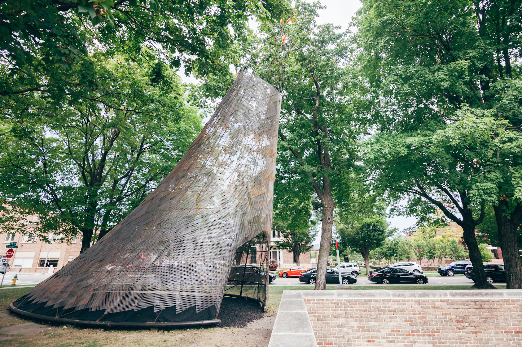 Large metal triangular-shaped hut sculpture in wooded park