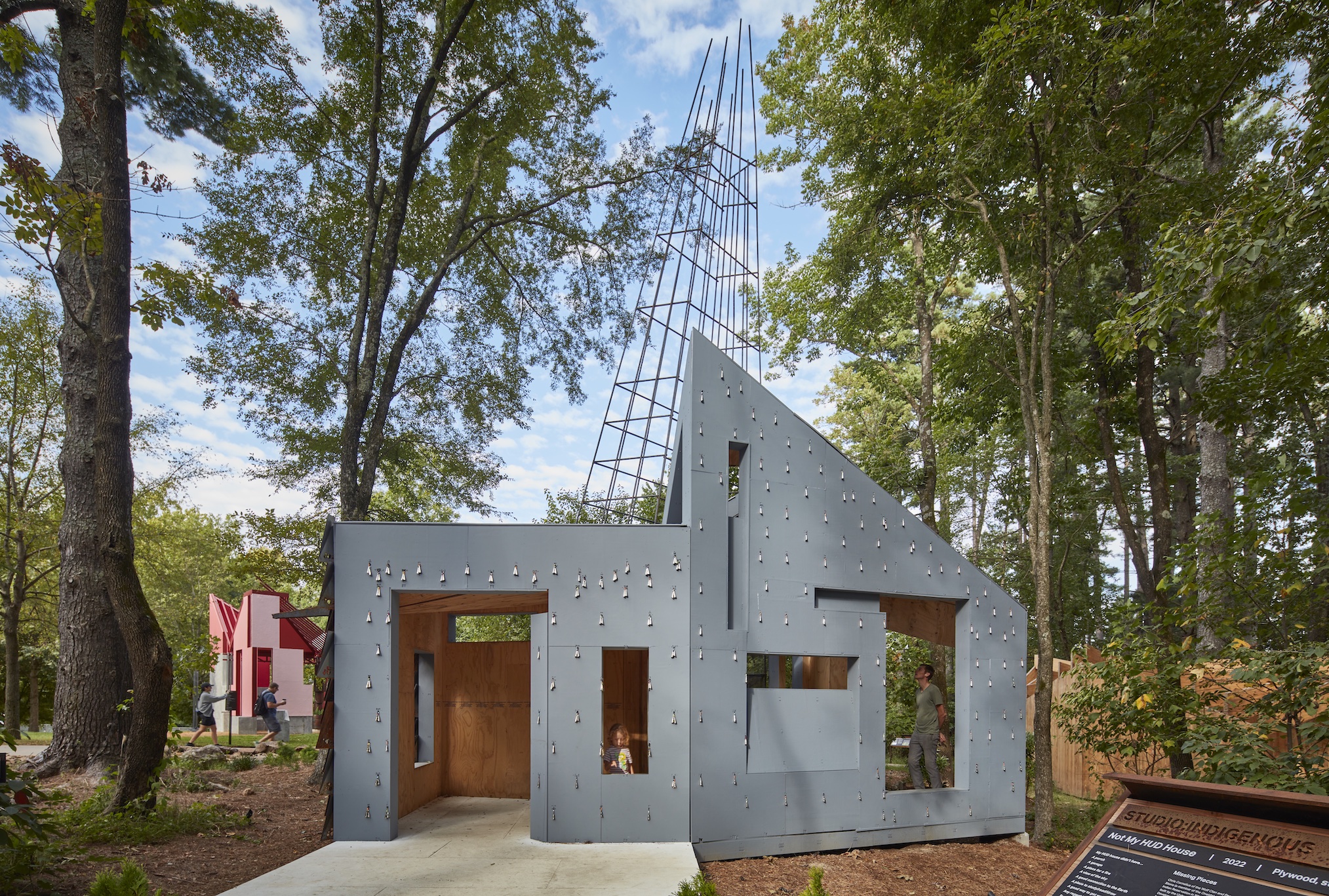 Wide shot of small gray modern assymetrical house designed by Chris Cornelius in the woods