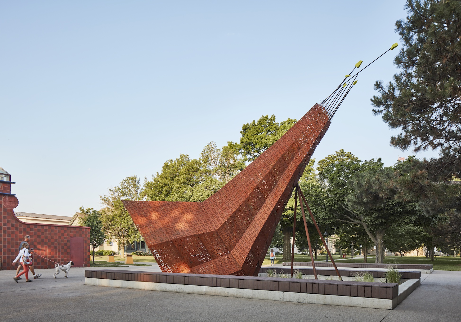 Large outdoor abstract triangle-shaped sculpture by Christopher Cornelius with people walking by