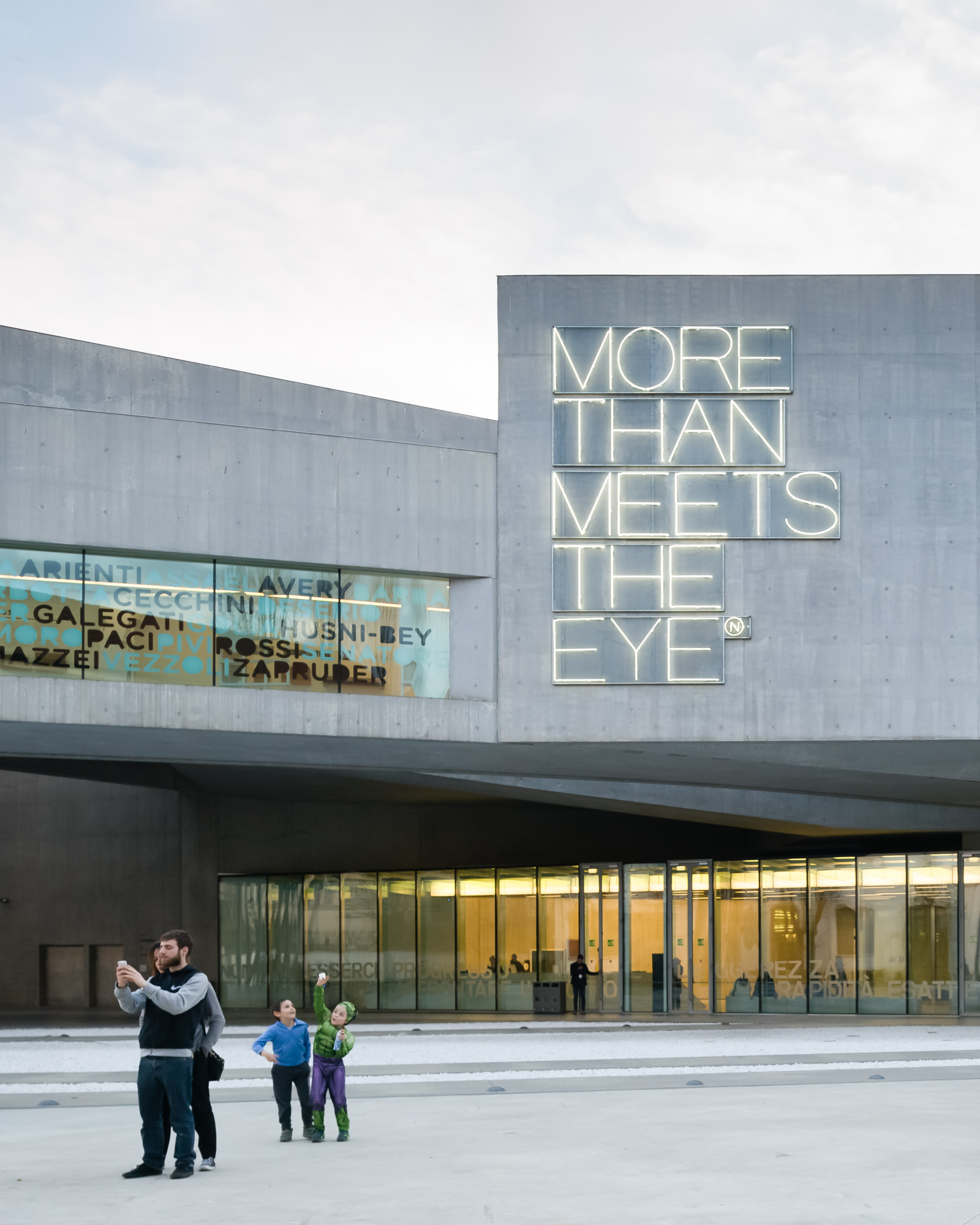 Candid shot of two parents and two children, one of whom is wearing a hulk costume, standing in front of Maxxi