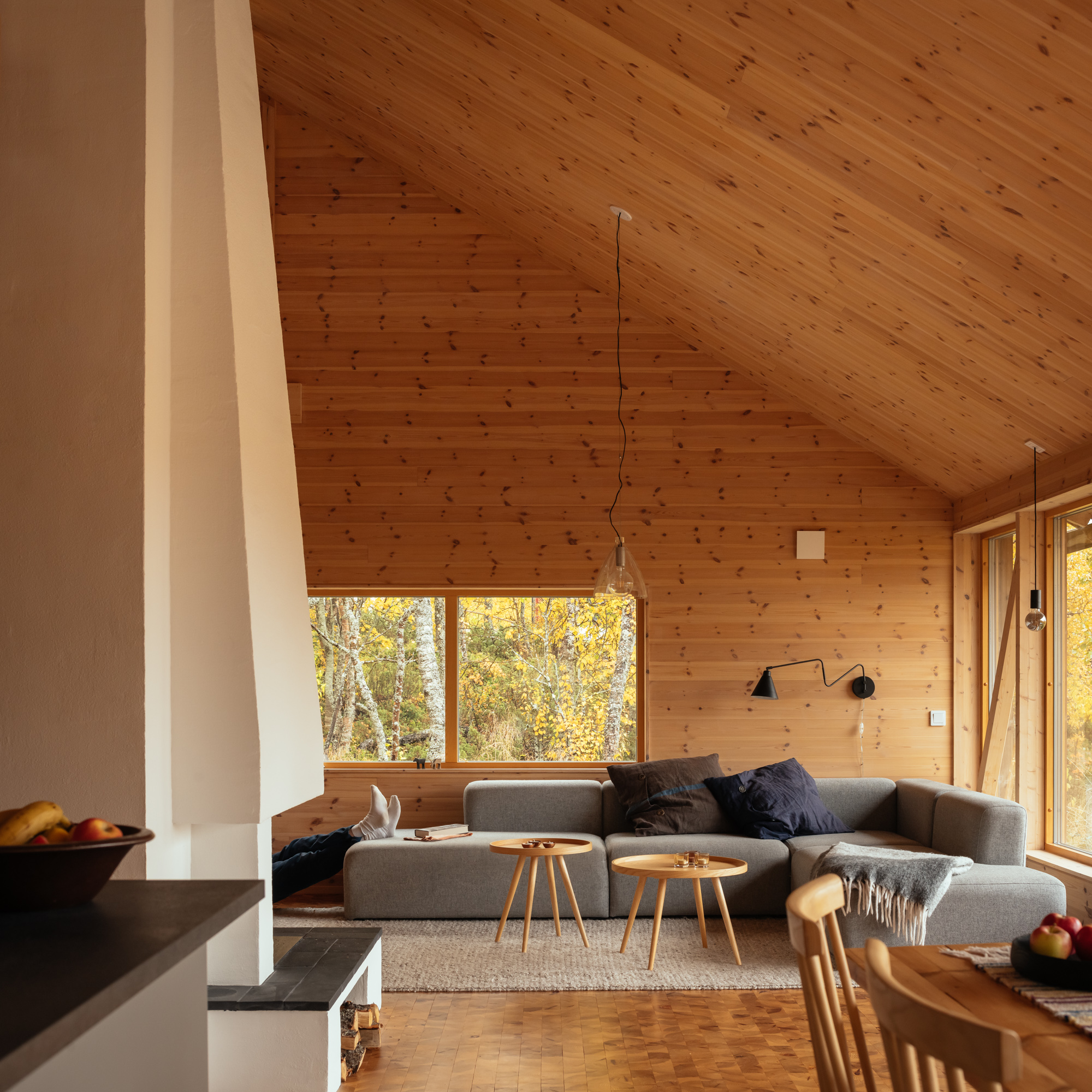 Interior shot of a modern wooden living room with the feet of someone lying down propped up on the couch